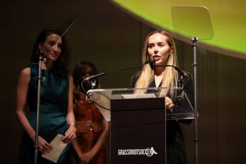 A woman in formal attire speaks at a podium.